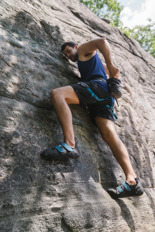 a man climbing up the side of a rock, featured on reddit, renaissance, wearing a tank top and shorts, birkenstock sandals, malaysian, highly technical