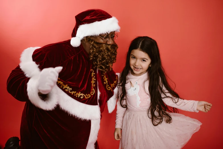 a little girl standing next to a santa clause, a photo, pexels, hurufiyya, with brown skin, - 6, 4yr old, chocolate
