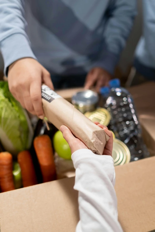 a person holding a knife in front of a box of food, getting groceries, square, thumbnail, brown