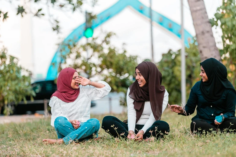 a group of women sitting on top of a grass covered field, by Ismail Acar, pexels contest winner, hurufiyya, sitting under bridge, dialogue, casual game, malaysian
