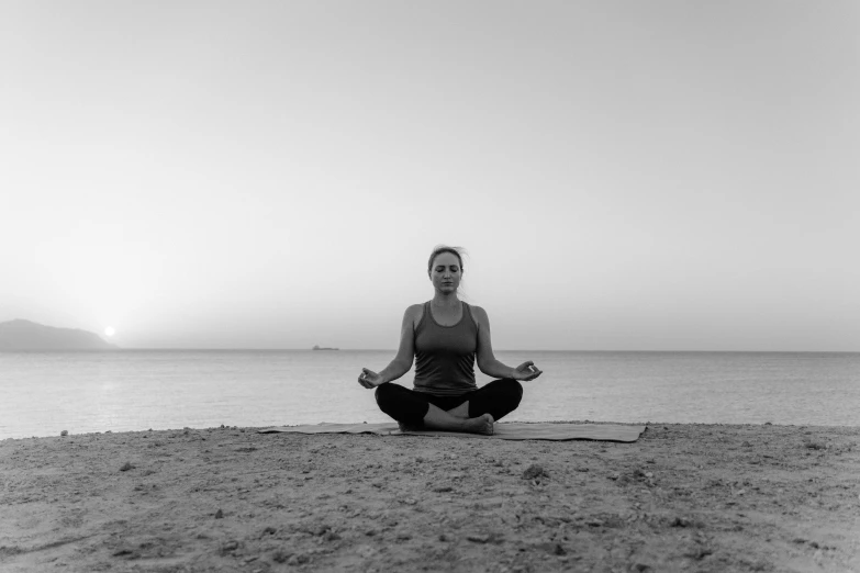 a woman is doing yoga on the beach, a black and white photo, pexels, calm evening, medium portrait, seated, symmetrical