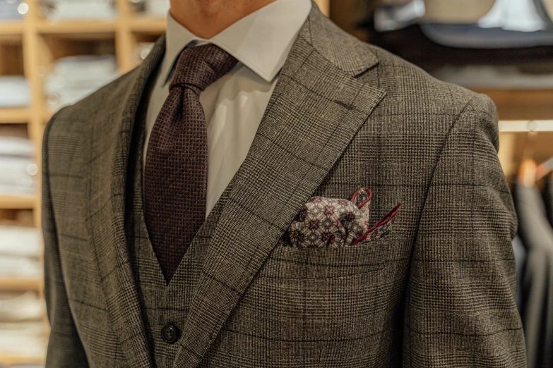 a close up of a suit on a mannequin mannequin mannequin mannequin mannequin mannequin manne, a digital rendering, by Daniel Lieske, instagram, shot with sony alpha 1 camera, checkered motiffs, maroon accents, wearing a brown