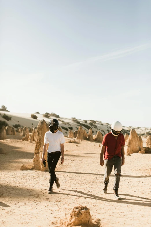 a group of people walking across a dirt field, at the desert, lee madgwick & liam wong, two handsome men, rock formations