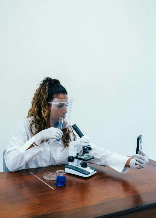 a woman in a lab coat using a microscope, pexels contest winner, snapchat photo, spanish, made of lab tissue, on a white table