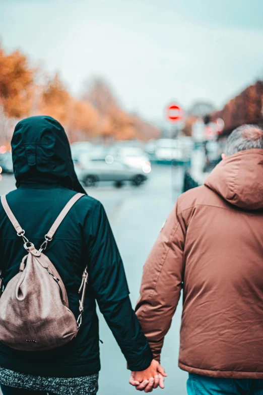 two people walking down the street holding hands, by Niko Henrichon, happening, wearing a hood, 🚿🗝📝, older male, her back is to us