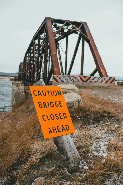 a close up of a sign near a body of water, trending on unsplash, graffiti, broken bridges, 2 5 6 x 2 5 6 pixels, warning, abandoned railroads