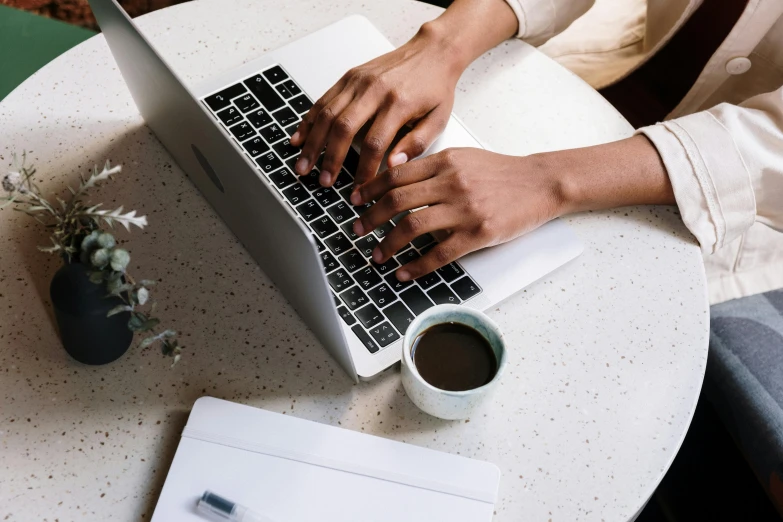 a woman sitting at a table typing on a laptop, by Carey Morris, trending on pexels, brown and white color scheme, high angle close up shot, with full descriptions, curated collections