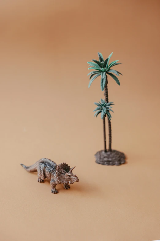 a small toy dinosaur standing next to a palm tree, a statue, by Andries Stock, trending on unsplash, weta studio, triceratops, detailed product image, tiny village