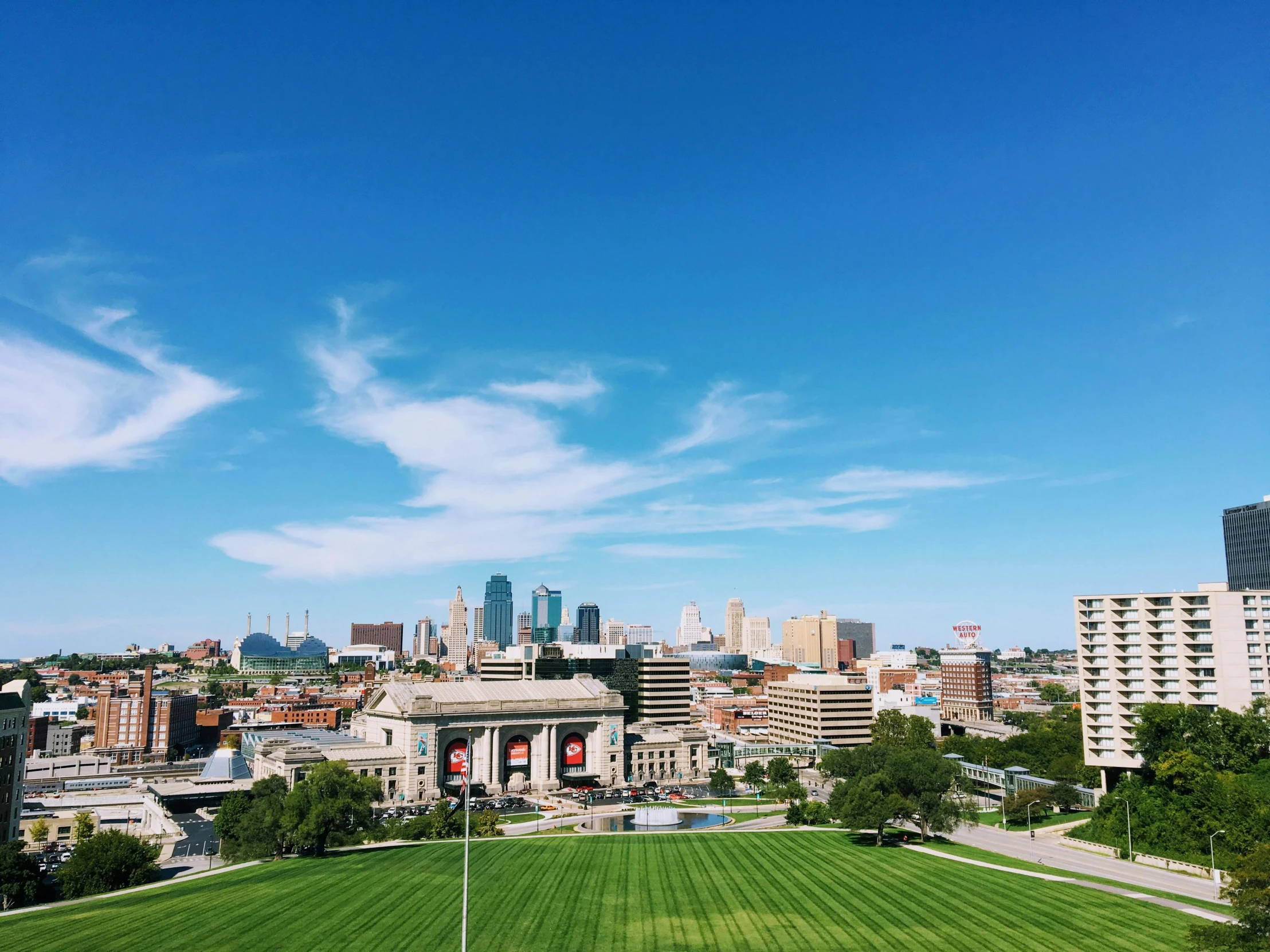 a view of a city from the top of a hill, by Kristin Nelson, pexels contest winner, visual art, park on a bright sunny day, oklahoma, clear blue skies, lawn