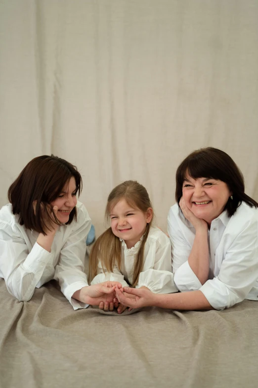 a group of women laying on top of a bed, a picture, by Helen Biggar, wearing lab coat and a blouse, family friendly, in front of white back drop, three women