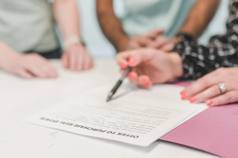 a close up of a person signing a document, by Carey Morris, pexels, group sit at table, heath clifford, thumbnail, background image