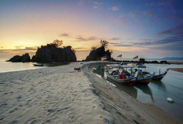 a couple of boats sitting on top of a sandy beach, by Bernardino Mei, unsplash contest winner, hurufiyya, malaysian, sunset panorama, island with cave, grey