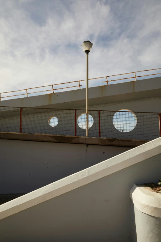 a man flying through the air while riding a skateboard, an abstract sculpture, inspired by Ned M. Seidler, brutalism, circular gate in a white wall, nazare (portugal), bridges and railings, light circles