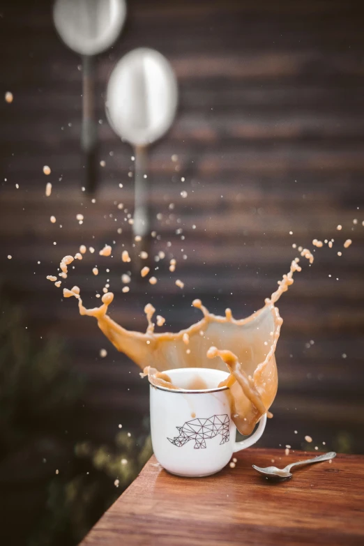 a cup of coffee and a spoon on a table, by Julia Pishtar, pexels contest winner, splashing water, caramel. rugged, leaping with arms up, holiday season