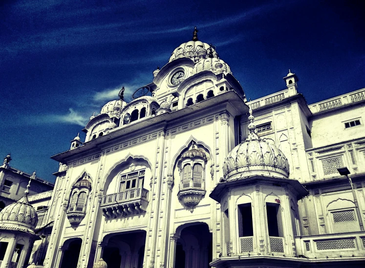 a large white building with a clock on the top of it, an album cover, inspired by Sardar Sobha Singh, flickr, baroque, eyes!, stunning grand architecture, blue, lomo