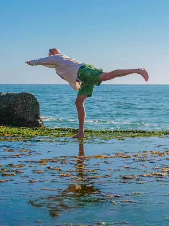 a man doing a handstand on the beach, by Jan Rustem, arabesque, seaweed floating, lachlan bailey, standing on rock, profile image