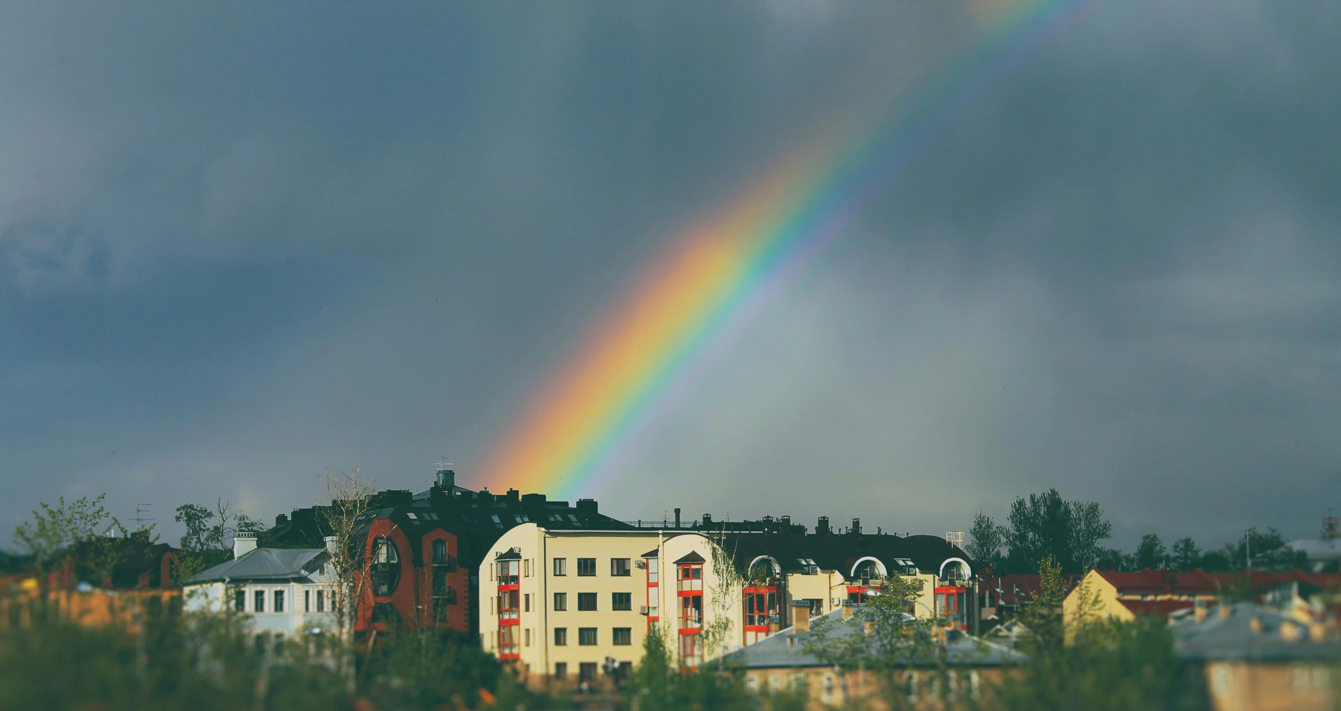 a rainbow is in the sky over a city, pexels contest winner, hurufiyya, espoo, still of rainbow ophanim, college, grey