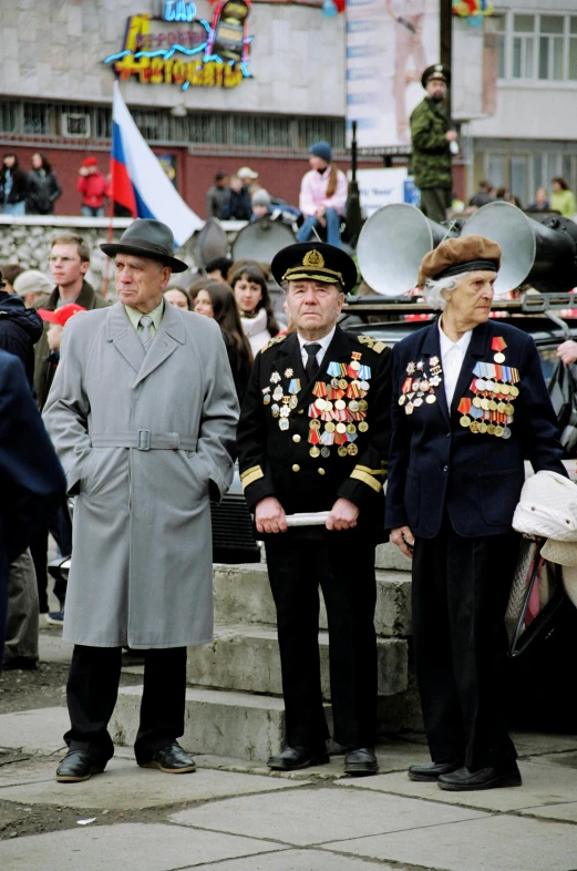 a group of men standing next to each other, a colorized photo, by Attila Meszlenyi, socialist realism, an oversized beret, wearing many medallions, spectators, taken in the late 2000s