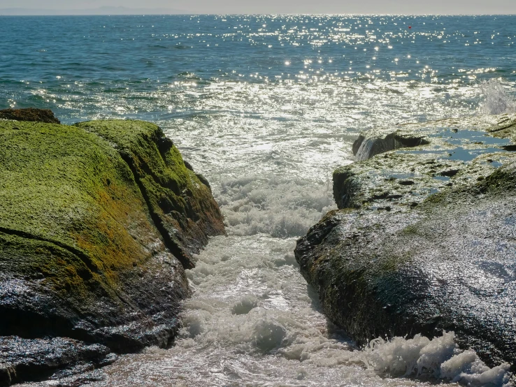 a body of water that is next to some rocks, a picture, inspired by William Trost Richards, unsplash, happening, sparkling in the sunlight, earthwave, green sea, silver light