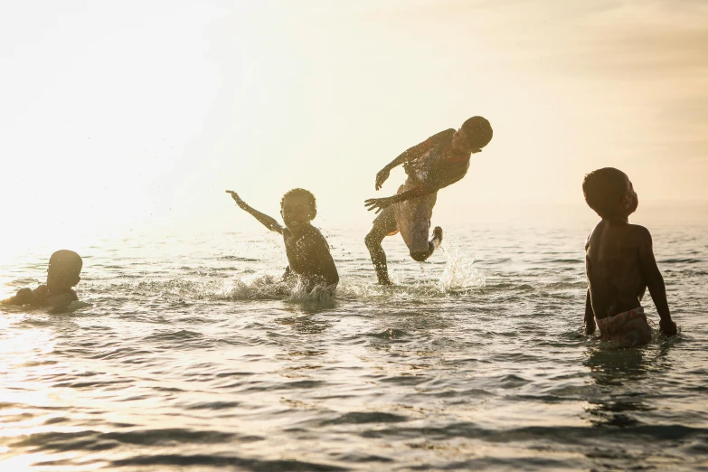 a group of children playing in the water, by Jessie Algie, pexels contest winner, warm light, reggae, aboriginal, subtle details