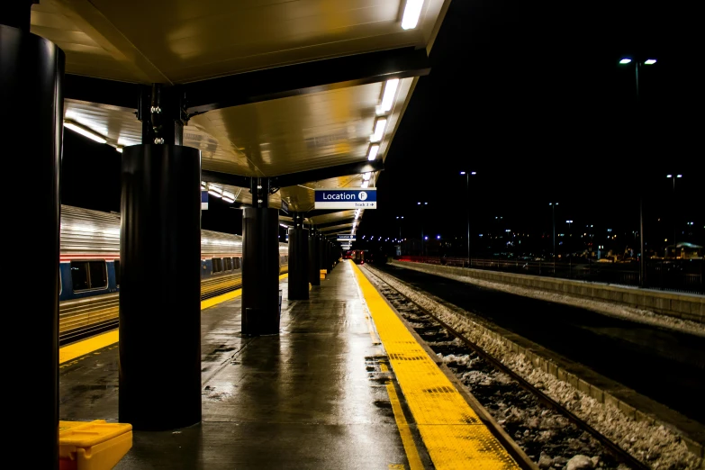 a train pulling into a train station at night, by Carey Morris, unsplash, square, benches, seattle, blue and yellow lighting