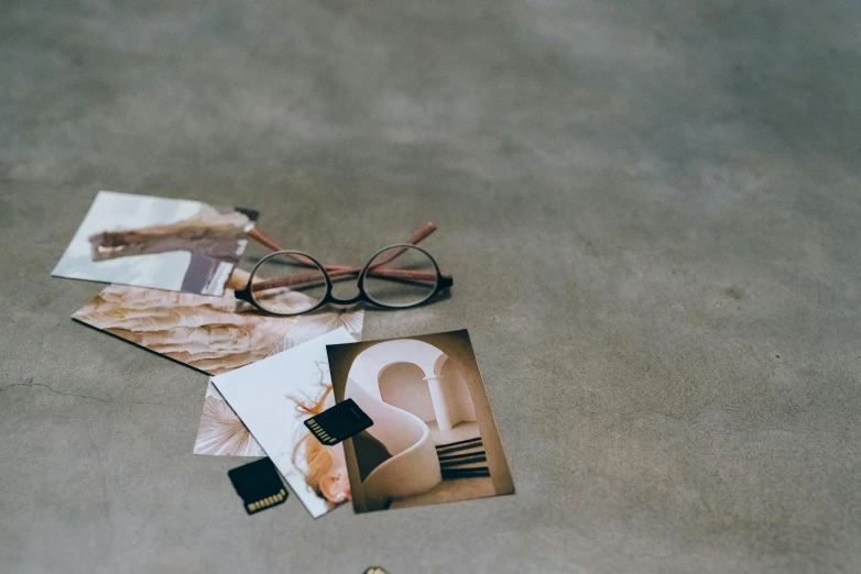 a pair of glasses sitting on top of a table, a polaroid photo, trending on pexels, visual art, moodboard, pair of keycards on table, muted browns, clear curvy details