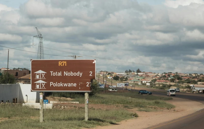 a brown street sign sitting on the side of a road, by Hubert van Ravesteyn, view of villages, yotobi, highway, grey