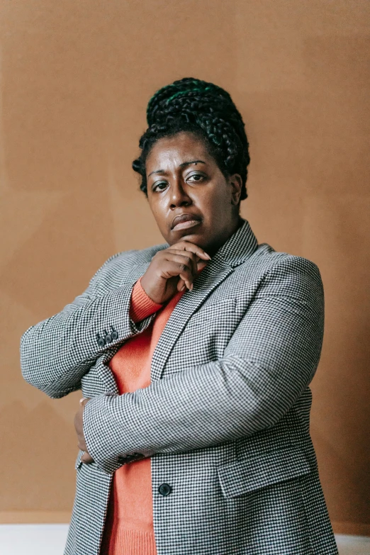 a woman standing in front of a brown wall, by Lily Delissa Joseph, wearing a worn out brown suit, riyahd cassiem, on clear background, concerned expression