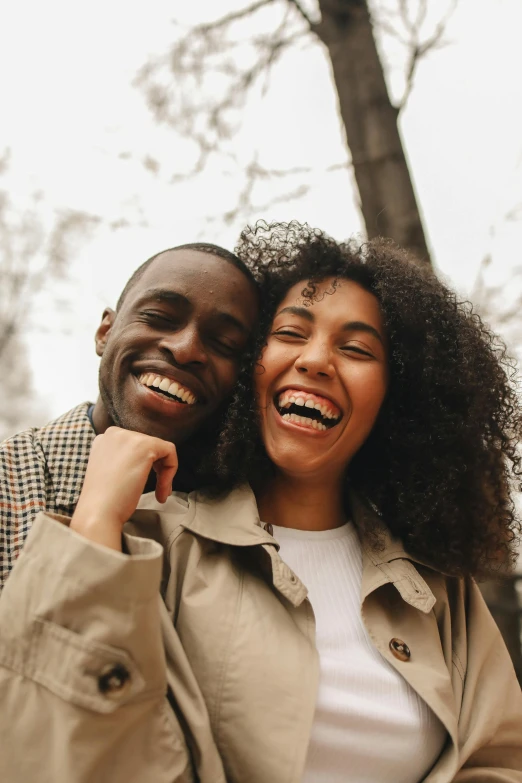 a man and a woman standing next to each other, trending on pexels, happening, large black smile, embracing, brown, cheeks