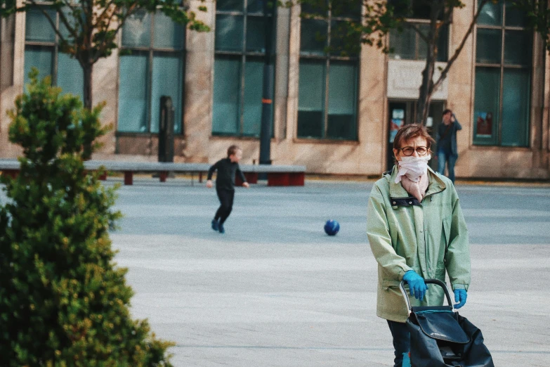 a woman wearing a face mask pushing a stroller, pexels, happening, city square, avatar image, romanian, a green