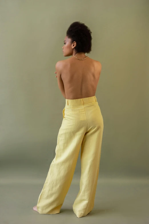 a woman standing with her back to the camera, hansa yellow, large pants, mid-20s, ashteroth