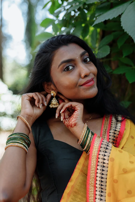 a woman in a yellow sari talking on a cell phone, wearing ornate earrings, with kerala motifs, curated collection, wearing intricate black choker