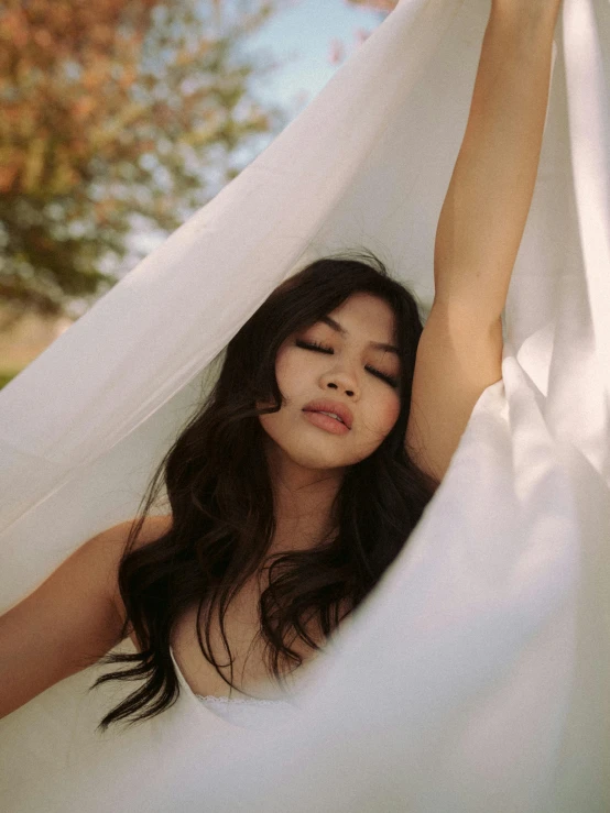 a woman laying in a hammock with her eyes closed, inspired by Ruth Jên, happening, wearing organza gown, joy ang, waving at the camera, wearing white camisole