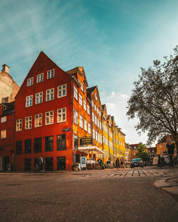 a red building sitting on the side of a road, by Jesper Knudsen, pexels contest winner, art nouveau, beautiful late afternoon, cobblestone streets, denmark, square
