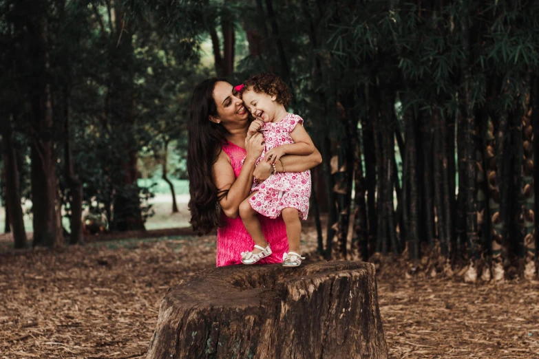 a woman holding a little girl on top of a tree stump, a portrait, by Lucia Peka, pexels contest winner, hurufiyya, pink, 3 5 year brazilian mother, 15081959 21121991 01012000 4k, forest picnic