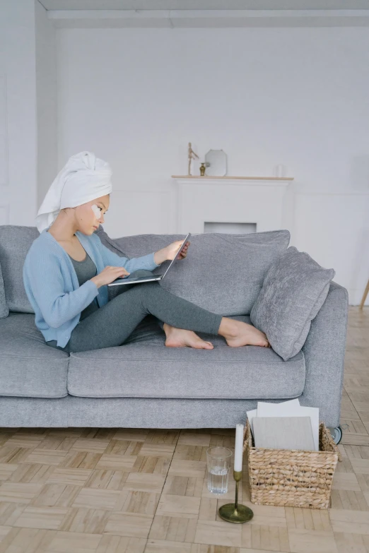 a woman sitting on a couch reading a book, wearing a white bathing cap, hijab, flat grey, working hard