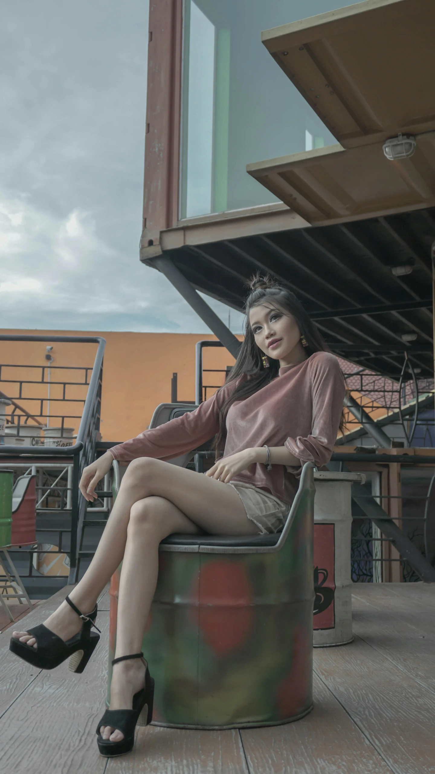 a woman sitting on top of a barrel next to a building, a colorized photo, inspired by Rudy Siswanto, pexels contest winner, aestheticism, sitting on an armchair, ((portrait)), brown clothes, evening time