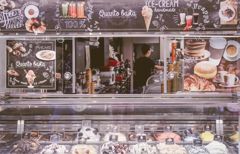 a display case filled with lots of different types of doughnuts, a picture, by Julia Pishtar, pexels contest winner, fantastic realism, ice cream on the side, urban surroundings, people shopping, desaturated