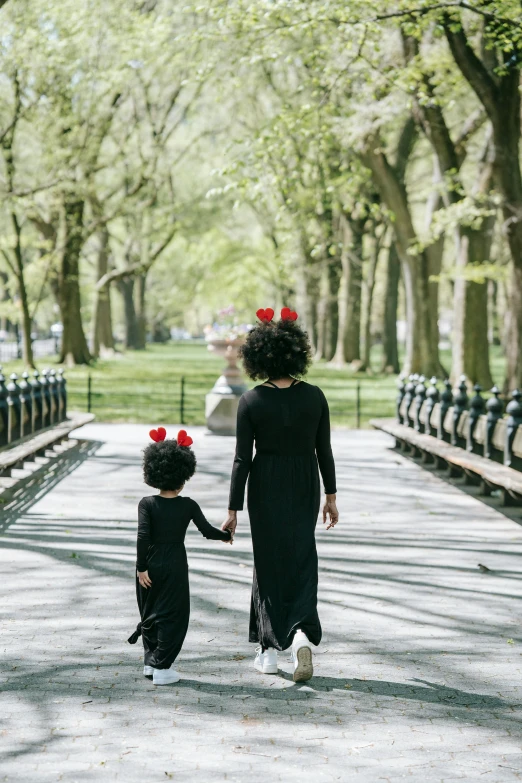 a woman and a child walking in a park, inspired by Gordon Parks, unsplash, harlem renaissance, black hair ribbons, crimson - black beehive, black robes, [ cinematic