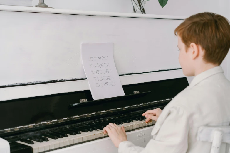 a little boy that is sitting in front of a piano, on a white table