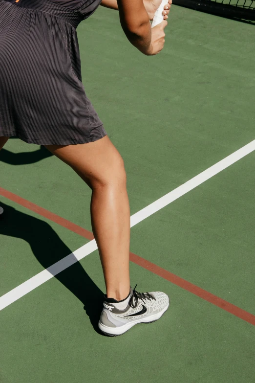 a woman holding a tennis racquet on a tennis court, by Niko Henrichon, trending on dribble, gray shorts and black socks, walking to the right, legs intertwined, high-body detail