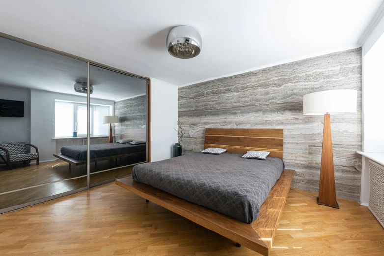 a bed sitting inside of a bedroom on top of a hard wood floor, inspired by Richard Wilson, unsplash, light and space, walnut wood, inside a modern apartment, stone and wood, wide - angle view