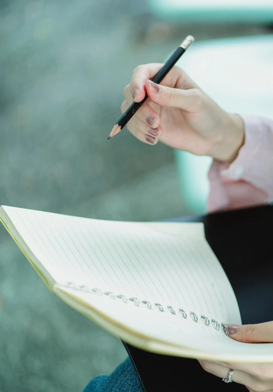 a woman holding a pen and writing in a notebook, getty images, ilustration, high quality picture, high resolution image