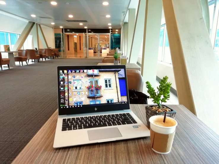 a laptop computer sitting on top of a wooden table, by Android Jones, pexels contest winner, happening, cybermosque interior, sitting in a waiting room, morning coffee, airport