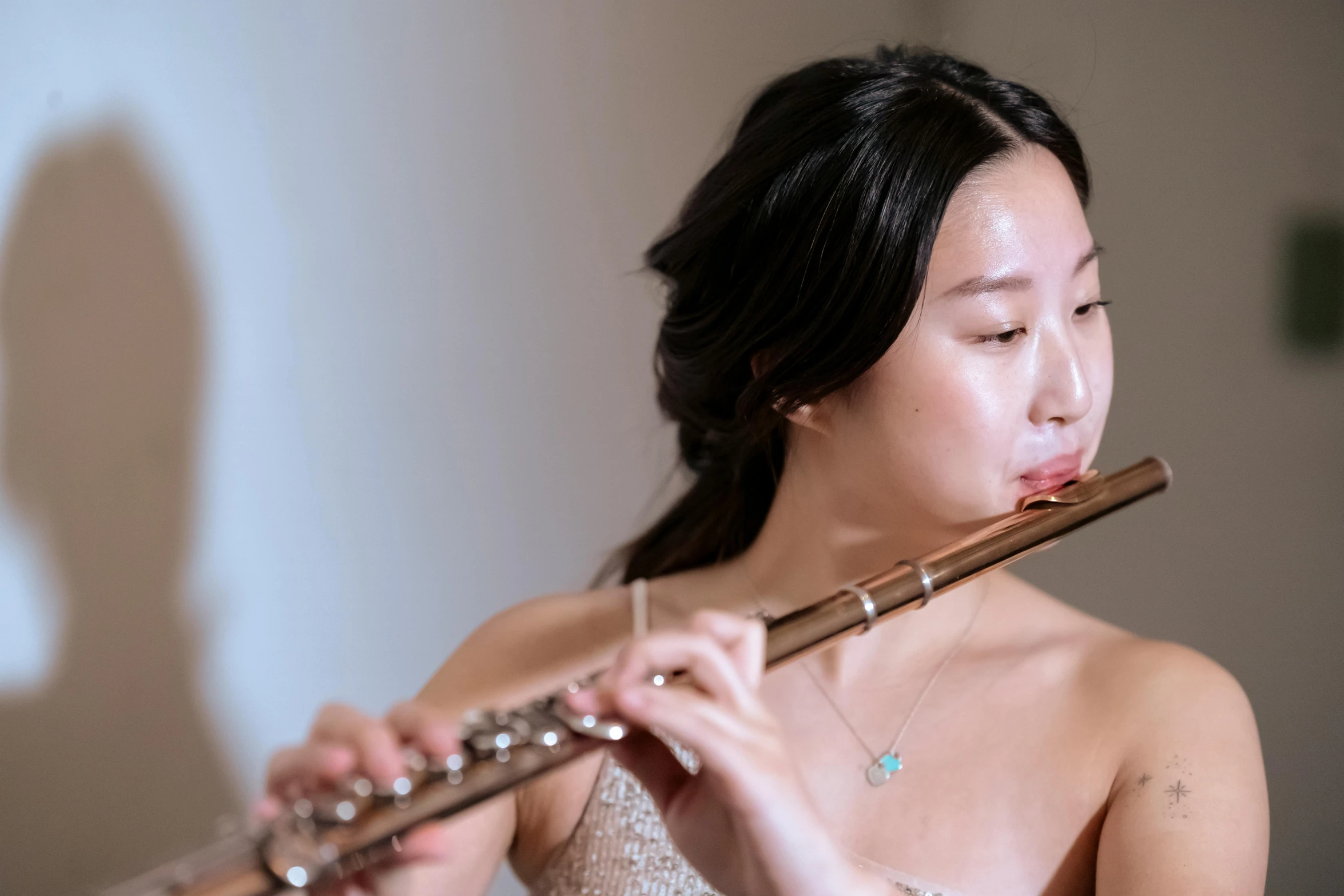 a woman playing a flute in a room, inspired by Zheng Xie, pexels contest winner, neck zoomed in, yanjun chengt, brittney lee, plain background