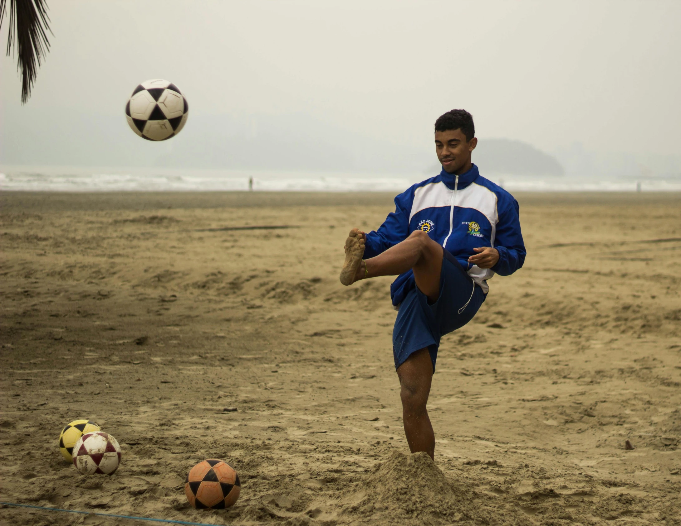 a man kicking a soccer ball on a beach, pexels contest winner, realism, peru, wearing a tracksuit, bhutan, working hard