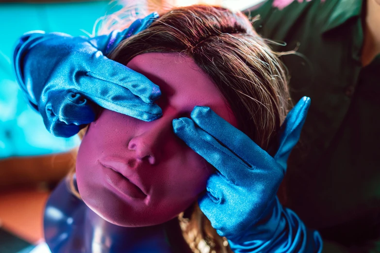 a woman with blue gloves covering her eyes, a hyperrealistic painting, trending on pexels, synthwave image, silicone skin, behind the scenes photo, bisexual lighting