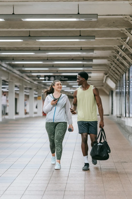 a couple of people walking down a hallway, subway station, wearing fitness gear, diverse, sydney hanson