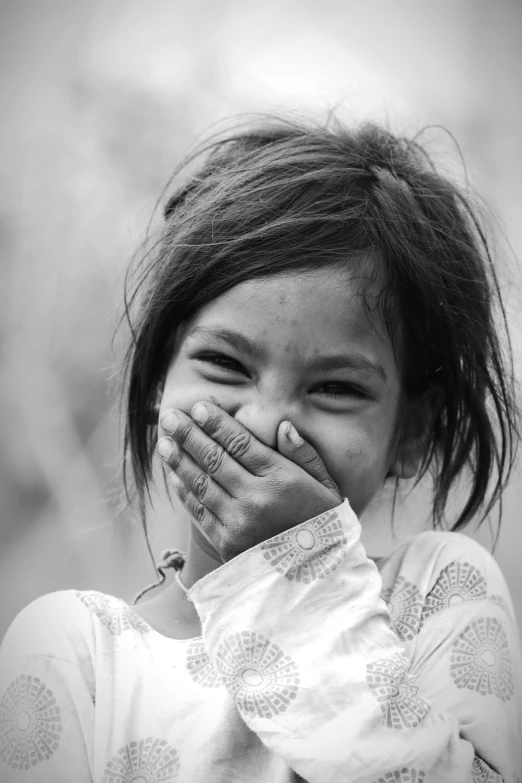 a little girl covering her face with her hands, a black and white photo, sumatraism, earing a shirt laughing, (beautiful) girl, nivanh chanthara, [[[[grinning evily]]]]