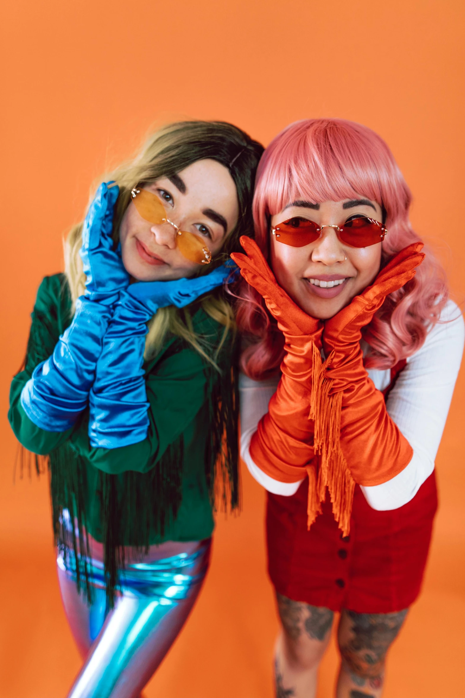 a couple of women standing next to each other, inspired by Wang Duo, trending on pexels, pop art, cosplayer dressed like a crab, gloves on hands, sunglasses and a scarf, fluffy orange skin